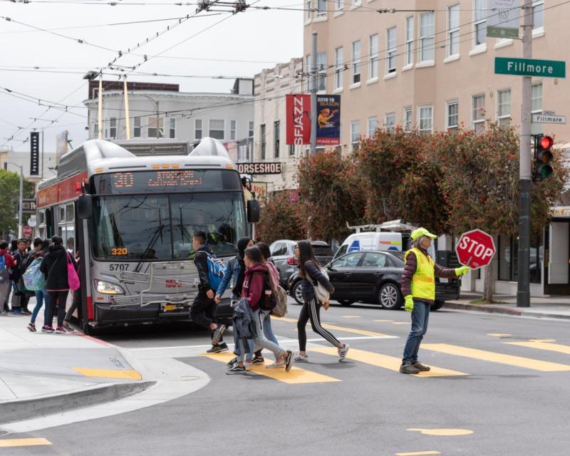 Students boarding the 30 Stockton bus, as well as crossing the street to catch the bus. 