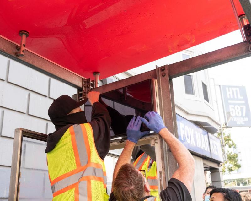 Crews working on a screen display at a bus stop