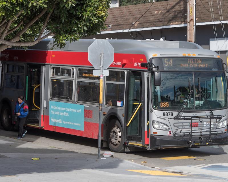 Coach approaching a bus stop along the curb with their door open. 