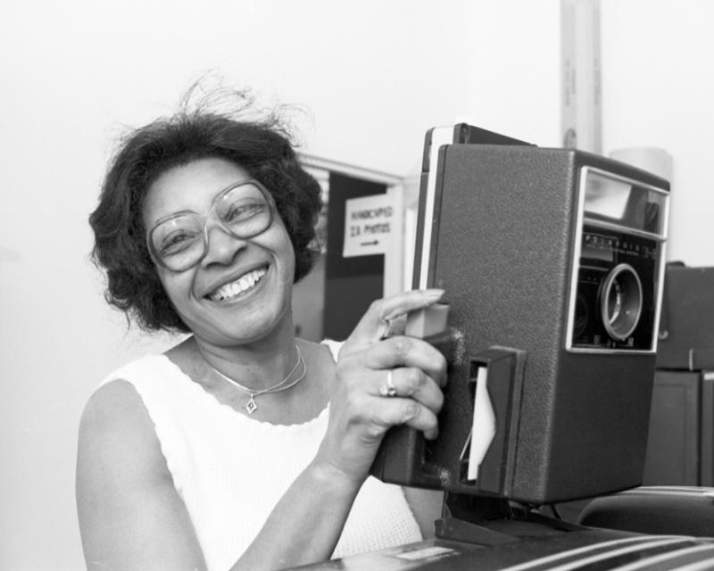 Employee smiling and holding a vintage card camera 