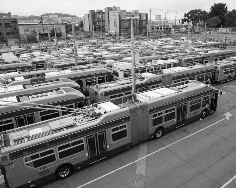 a high-angel view of a crowded bus yard, packed with trolley buses