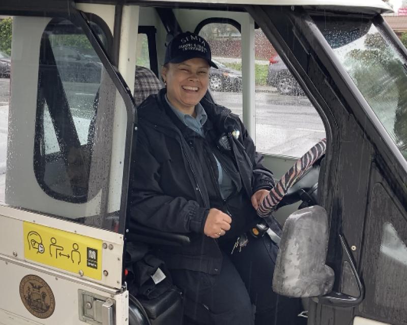 Parking Control Officer in uniform smiling while sitting inside a parking enforcement vehicle.