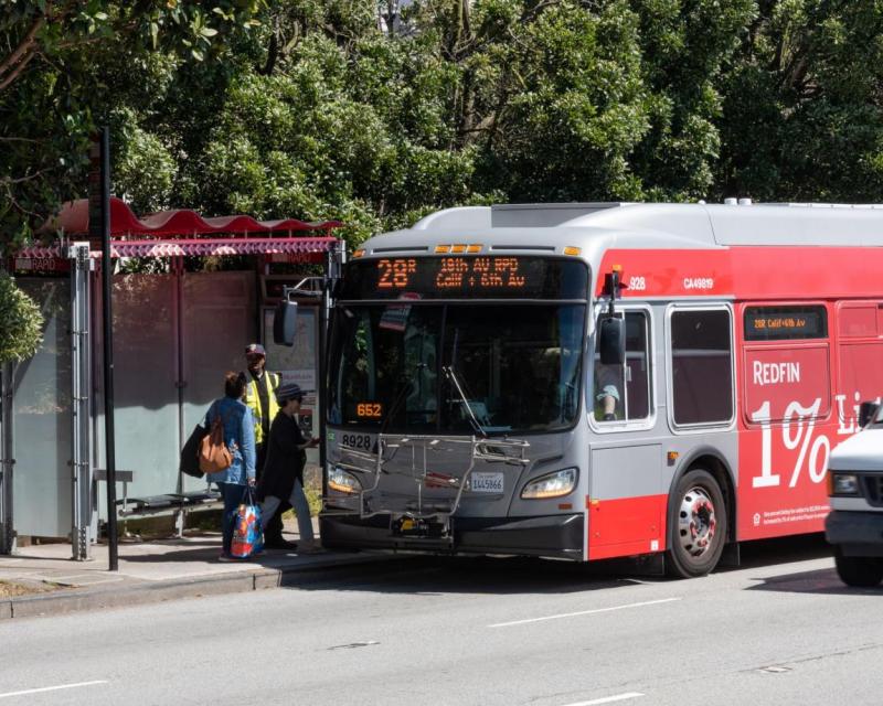 People at a bus stop boarding the 28R bus on 19th Avenue.