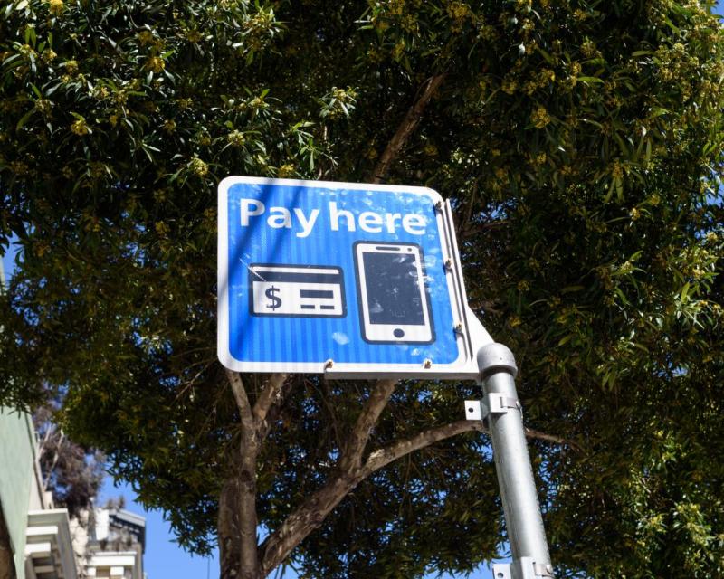 A sign that reads "Pay here" with a picture of a credit card and smartphone.