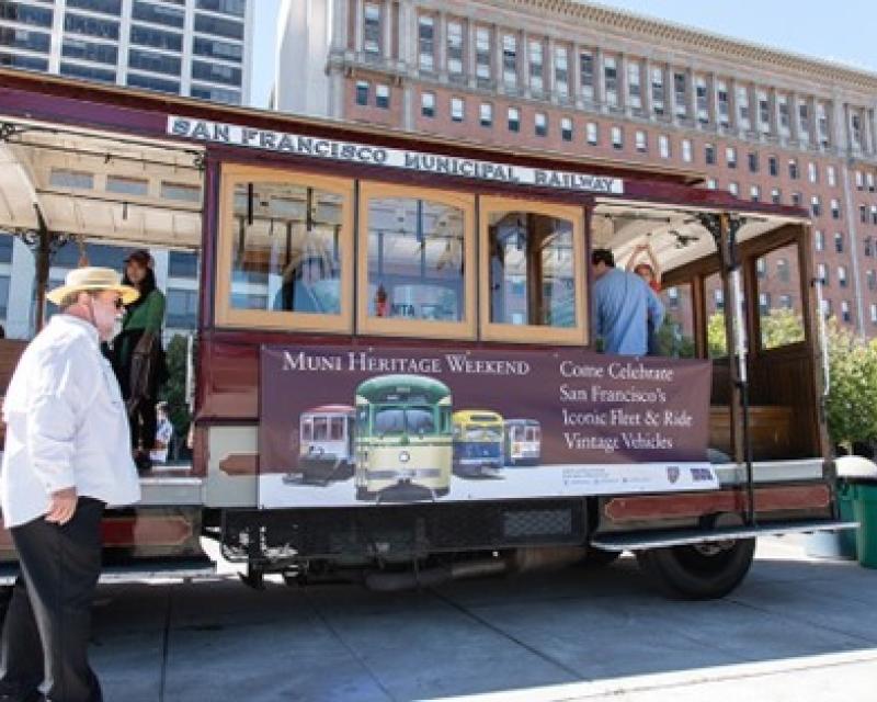 A San Francisco Cable Car with a banner that says Muni Heritage Weekend on the side.
