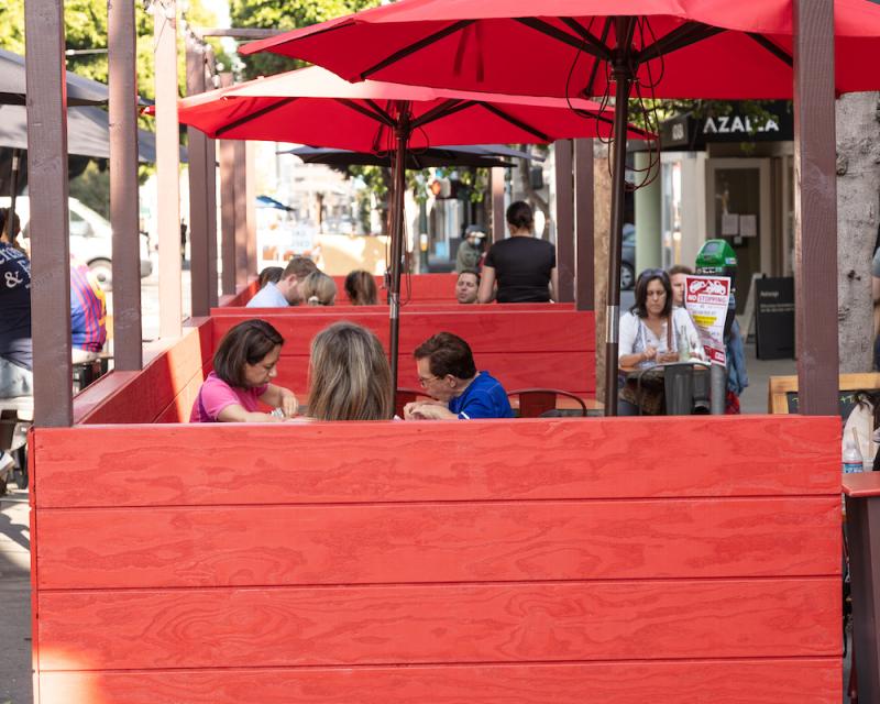 People eating in an outdoor enclosure at a restaurant.