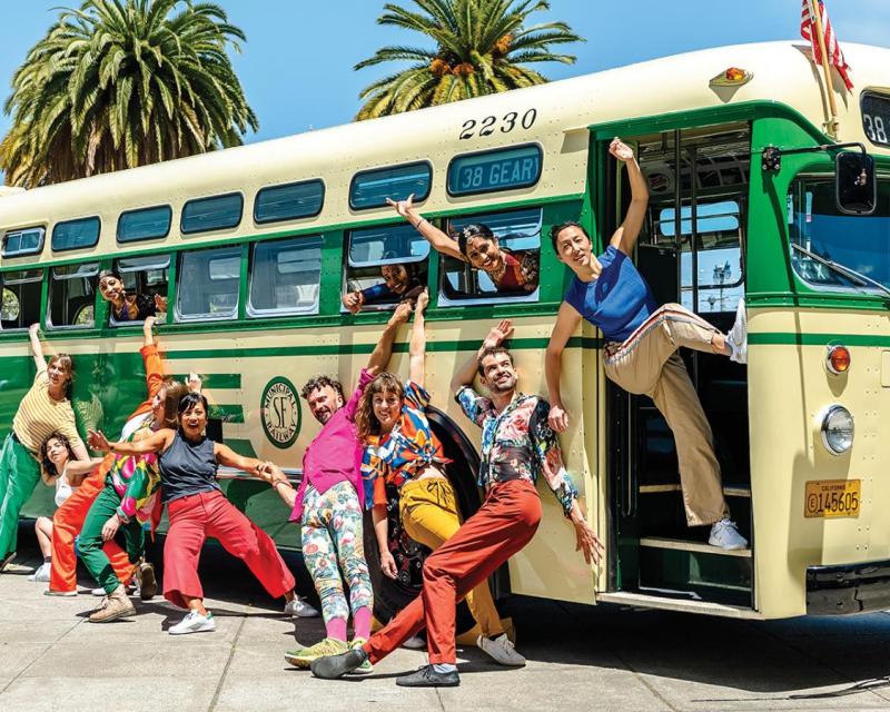 A group of people pose around a vintage bus.