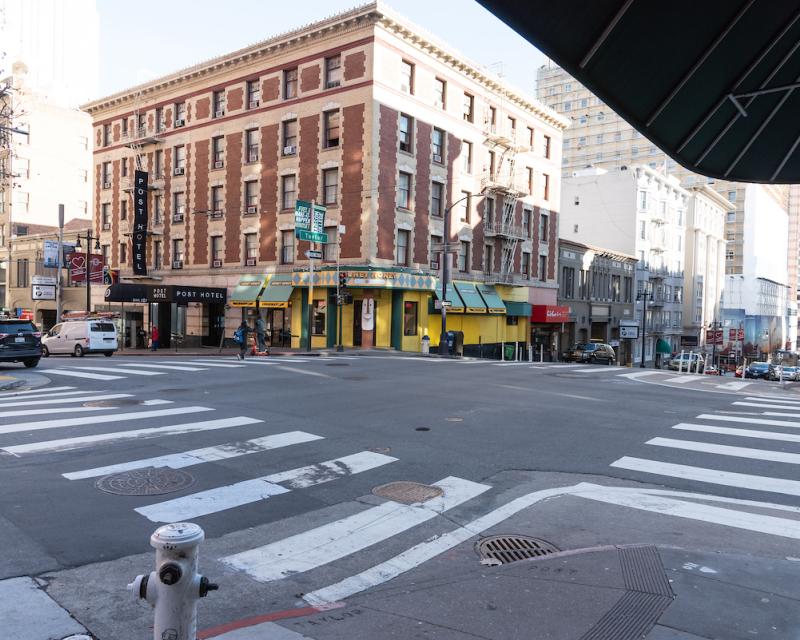 An intersection in San Francisco with crosswalks and surrounding tall buildings.