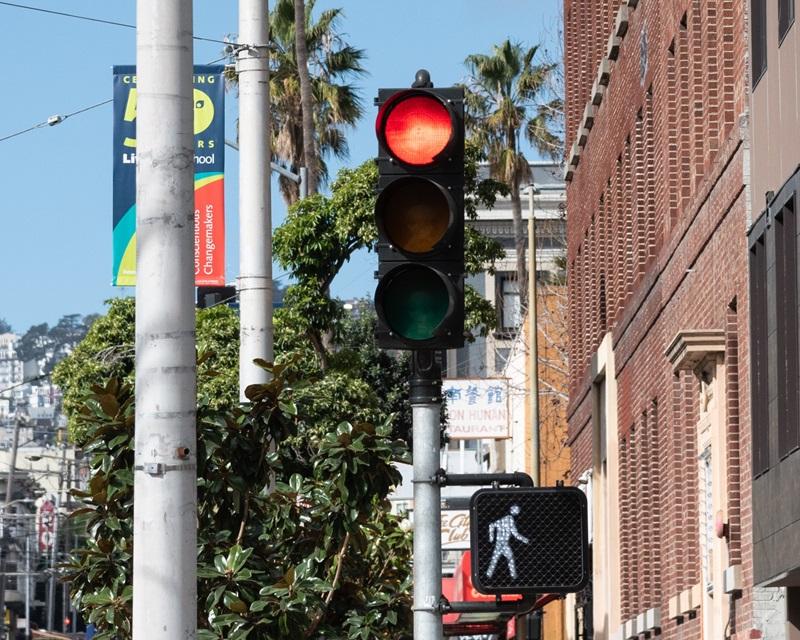 A red vehicular traffic signal adjacent to a white, pedestrian walk signal.