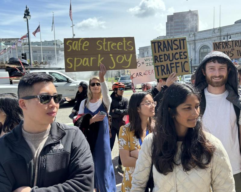 People on a sidewalk, some holding signs.