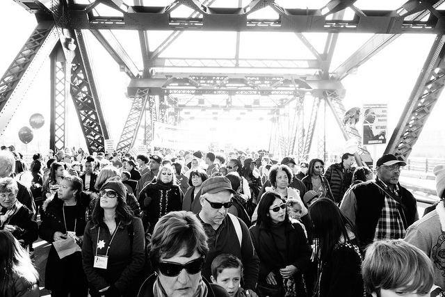 People walking over a bridge toward downtown San Francisco during the late morning.