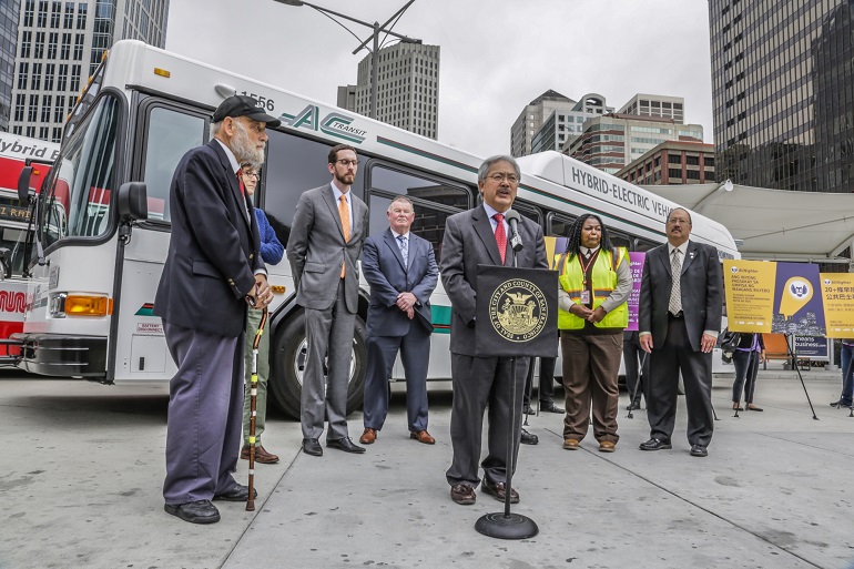 Mayor Ed Lee speaks at a press event at the Transbay Terminal in front of officials from Muni, AC Transit, SamTrans, Supervisor Scott Wiener and a Muni operator, all standing in front of AC Transit and Muni buses.