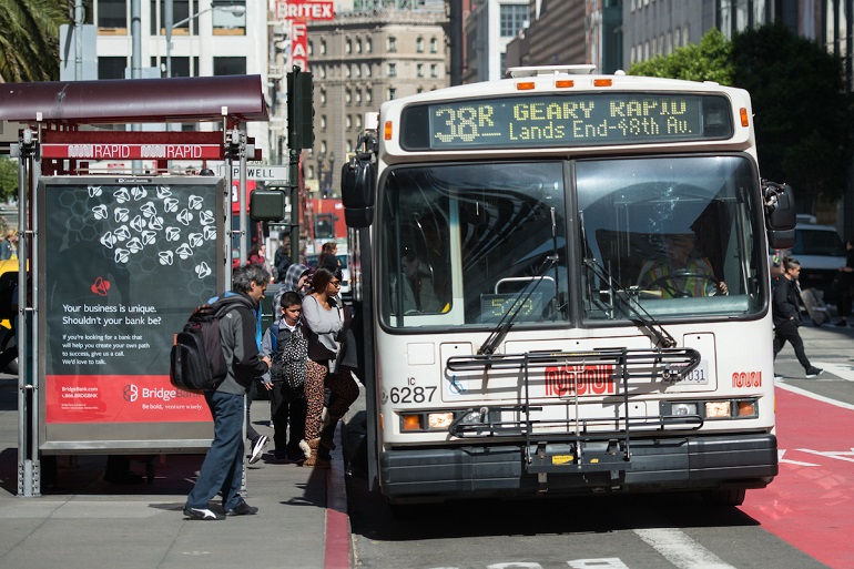 People board a 38R Geary Rapid bus stopped next to a red transit-only lane.