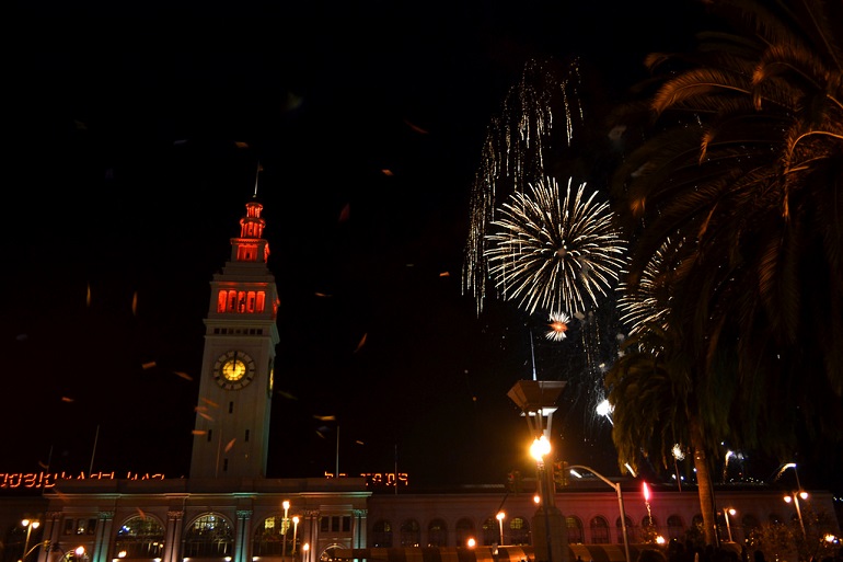 Ferry Building under a dark night sky with fireworks going off.