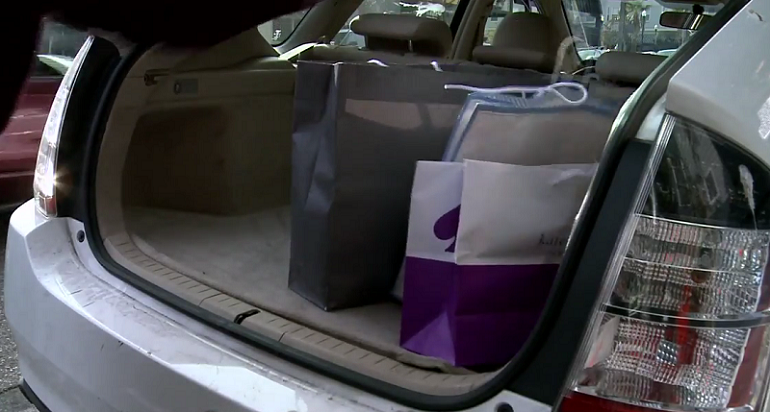 Shopping bags placed in an open car trunk.