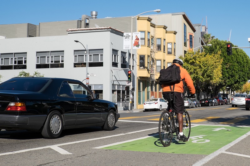 And man on bike and car traffic travel on Folsom Street at Russ Street.