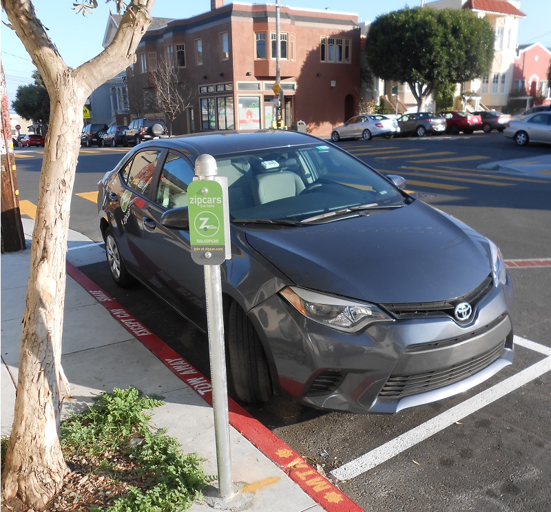 A car parked in a curbside parking space with car-share markings.