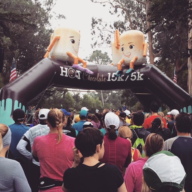 Runner at starting line in the park surrounded by green trees.