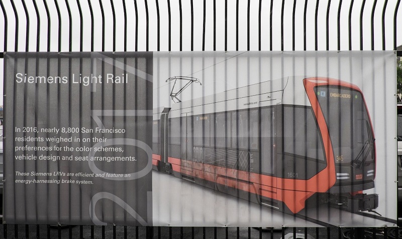 A section of the timeline banner on the Kirkland yard fence titled, "Siemens Light Rail," featuring a rendering of a new Muni light rail vehicle.