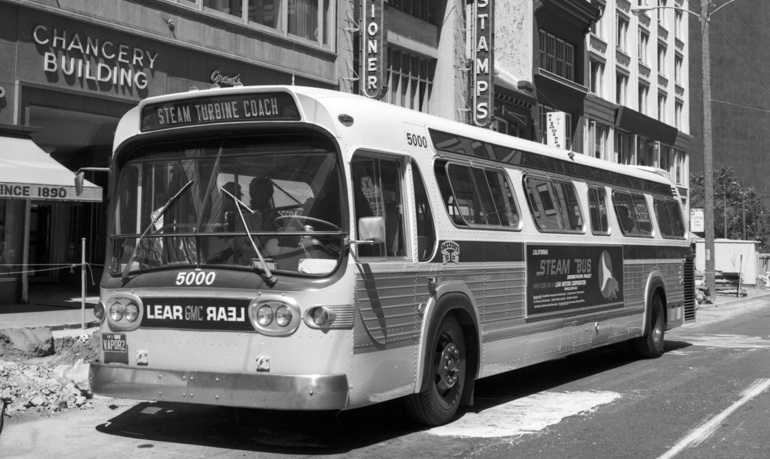 Black and white photo showing a GMC brand bus on Market Street near Sansome on August 23, 1972.  This bus is outfitted with a steam turbine engine for testing by Muni.