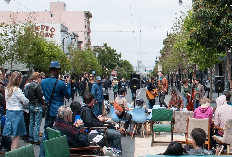  People watching a musical performance on a car-free roadway at Sunday Streets on Valencia Street.