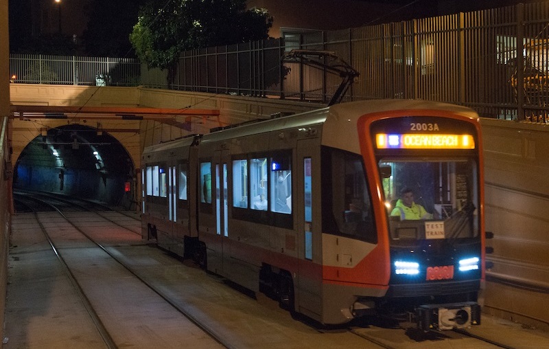 A new Muni train displaying a sign that says "Test Train" on the tracks just outside the Sunset Tunnel at night.