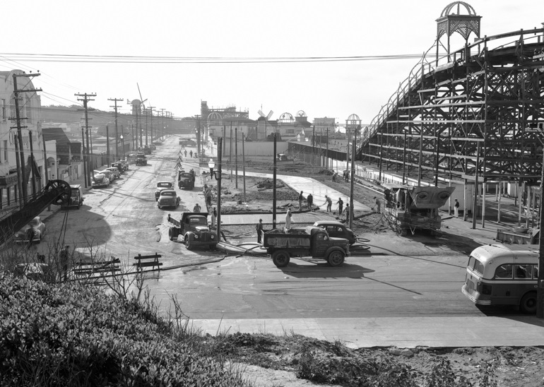 Black and white photograph looking south from Balboa and La Playa streets at construction of bus terminal in 1949.  To the right is a wooden amusement ride in Playland at the Beach amusement park.