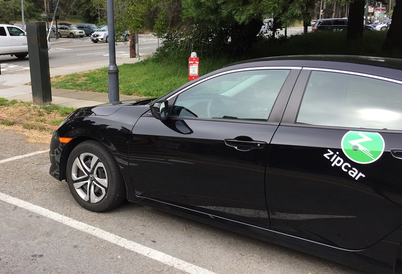 A car parked in a curbside parking space with marked for shared vehicles only.