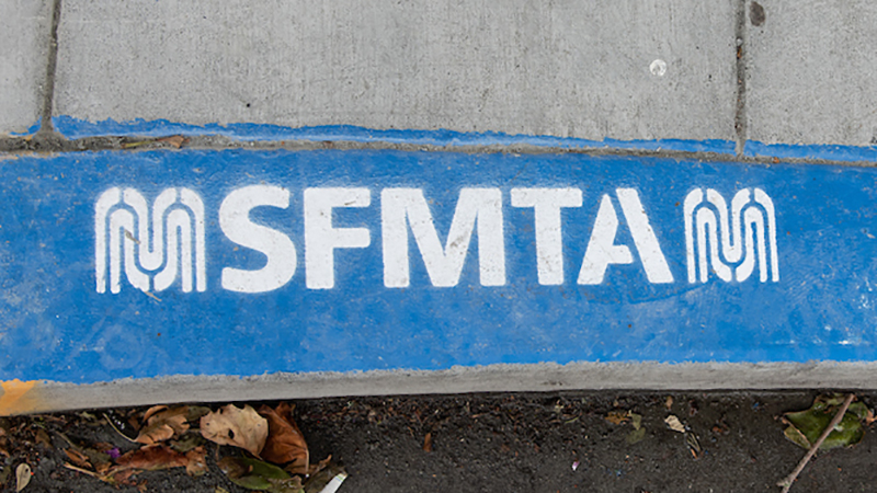 Blue painted curb with stencil that says "SFMTA"
