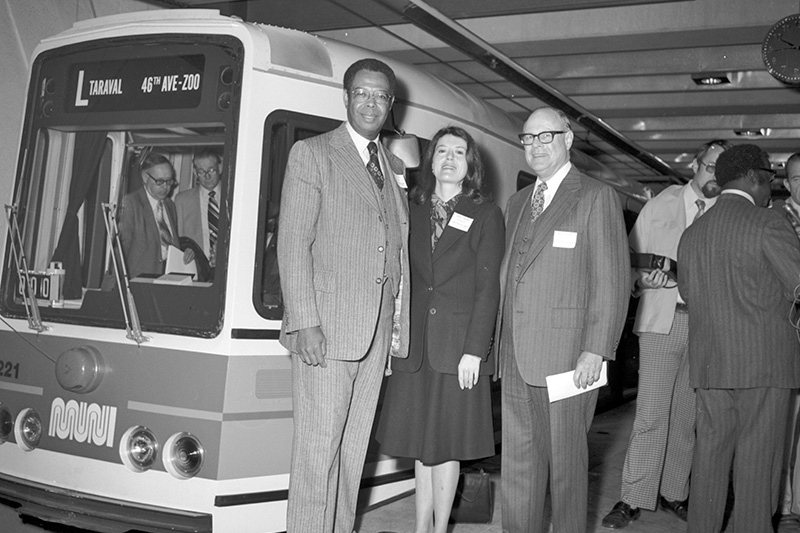 people standing next to Muni light rail vehicle in subway station