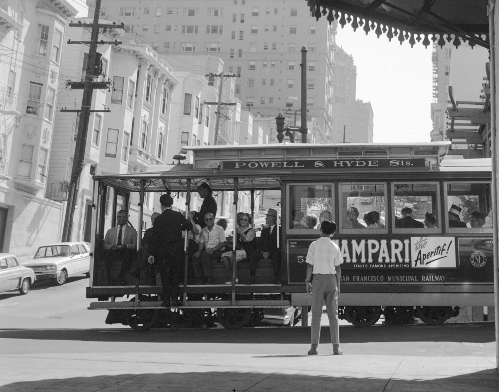 boy standing in front of passing cable car 