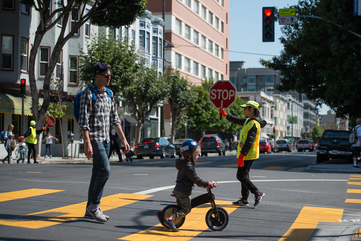 A crossing guard helping family cross the road. 