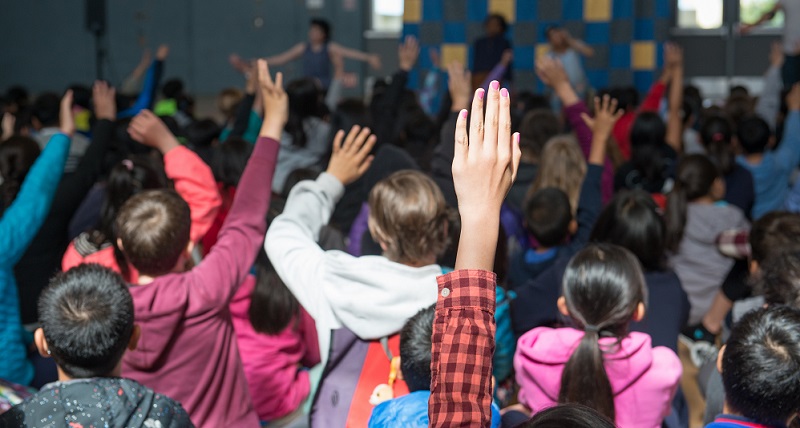 Kids in class raising their hands.