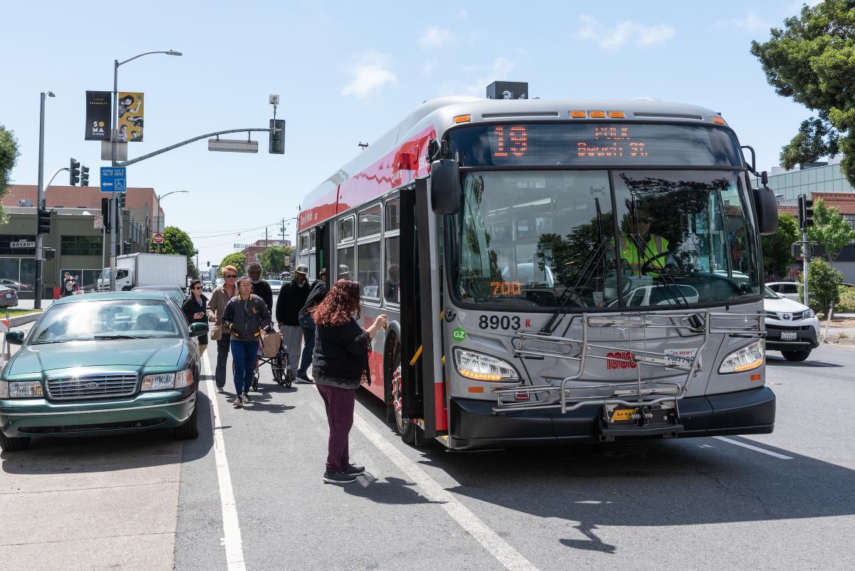 Passengers waiting in a bike lane to board a bus.