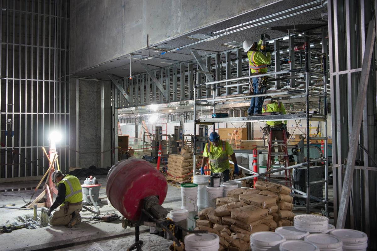 Pallets of terrazzo wait to be mixed while workers install conduits and structural steel at the future fare gate area for Yerba Buena/Moscone Station.