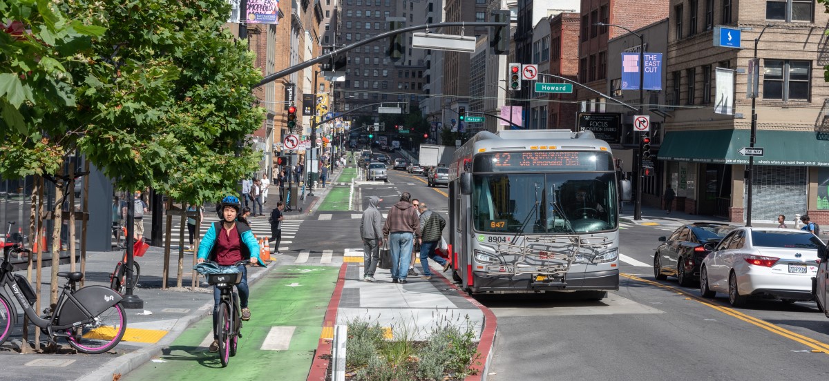 biker riding in the bike lane and a 12 Folsom-Pacific coach passing Howard Street