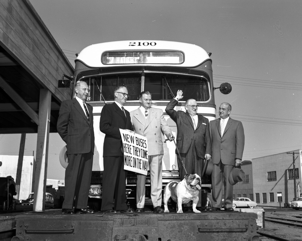 group of people with bulldog in front of bus