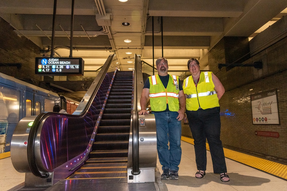 SFMTA staff standing in front of the escalator at Van Ness Station 