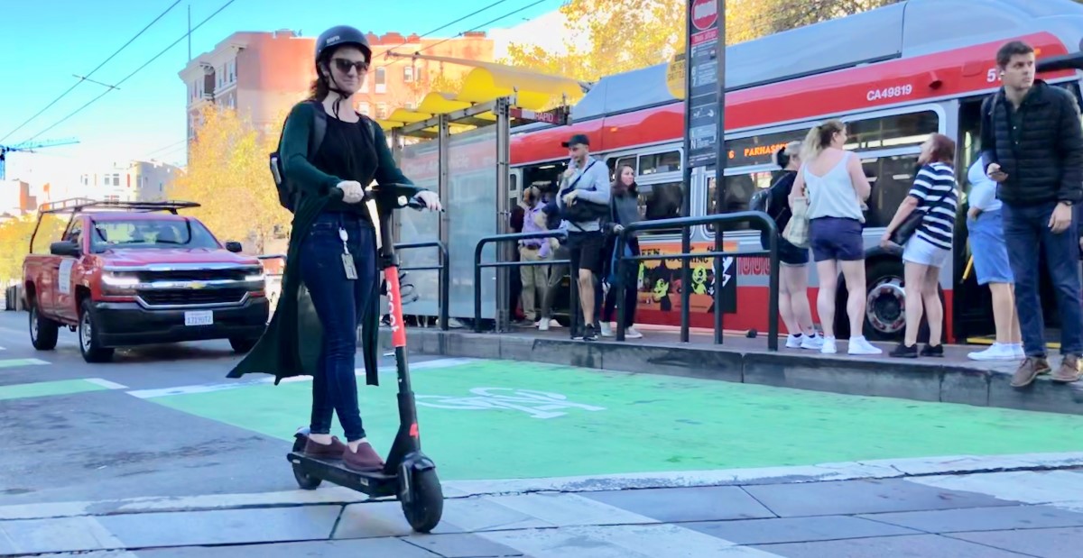 Lady on a scooter crossing Van Ness