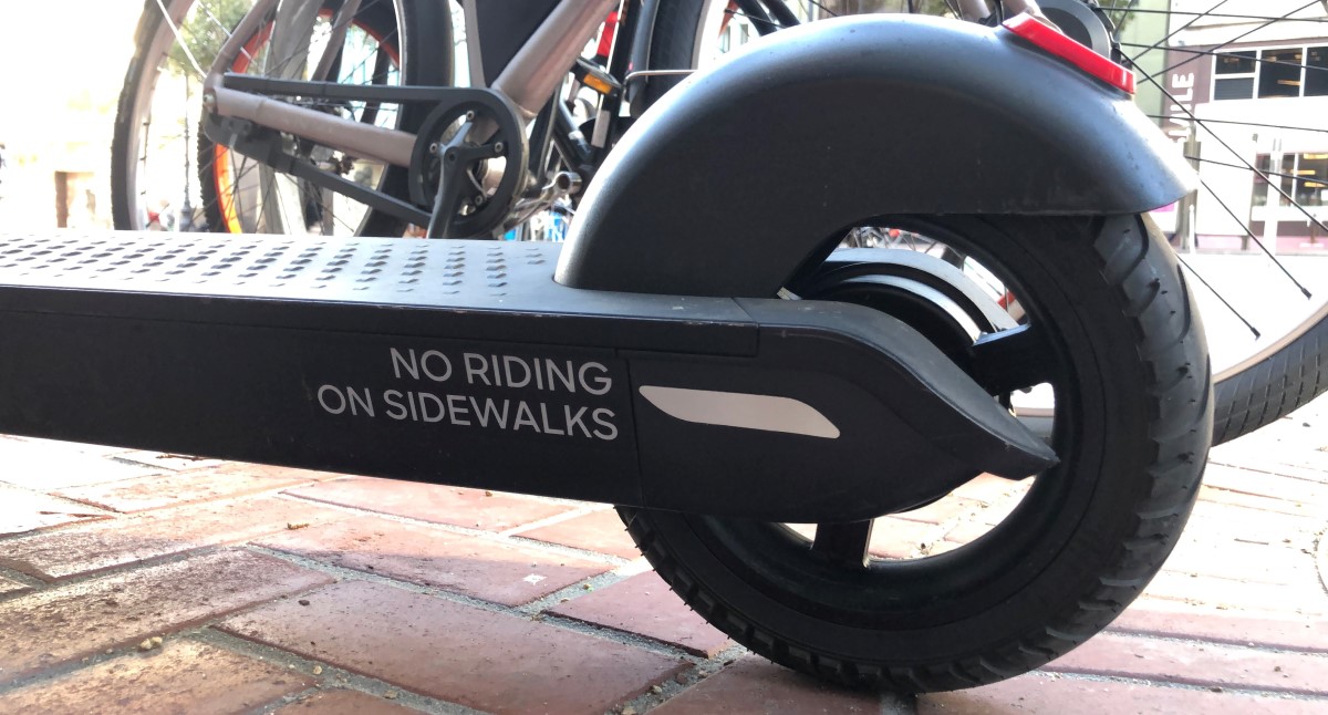 e scooter with "no riding on sidewalk" written on the side