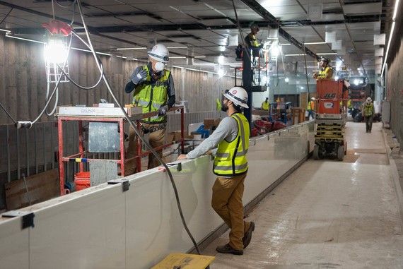 Crews install lighting, ceiling panels, and a public art array comprised of LED panels inside the south concourse.