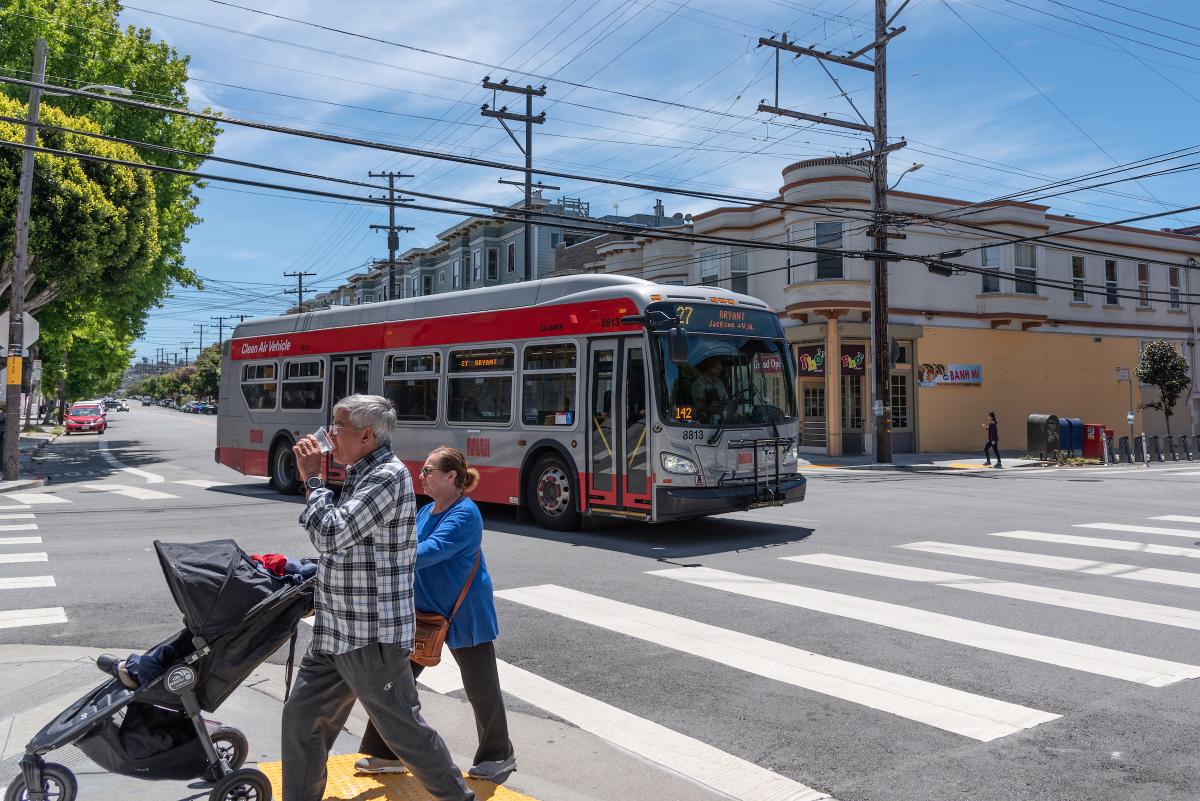 27 Bryant and two people crossing with a stroller on Bryant Street at 20th St in the Mission  