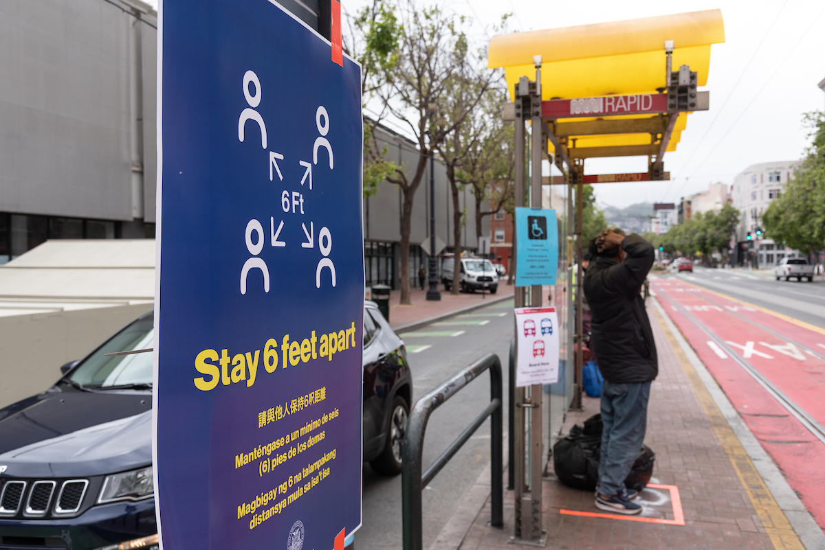 Signage and ground markings at Muni stops encourage physical distancing.