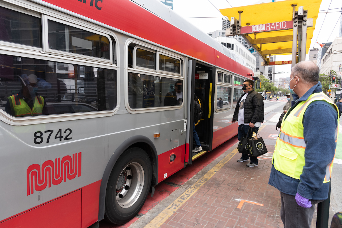 Muni Abmassador looks on as customer wearing a mask boards through the back after taking an essential trip for groceries.