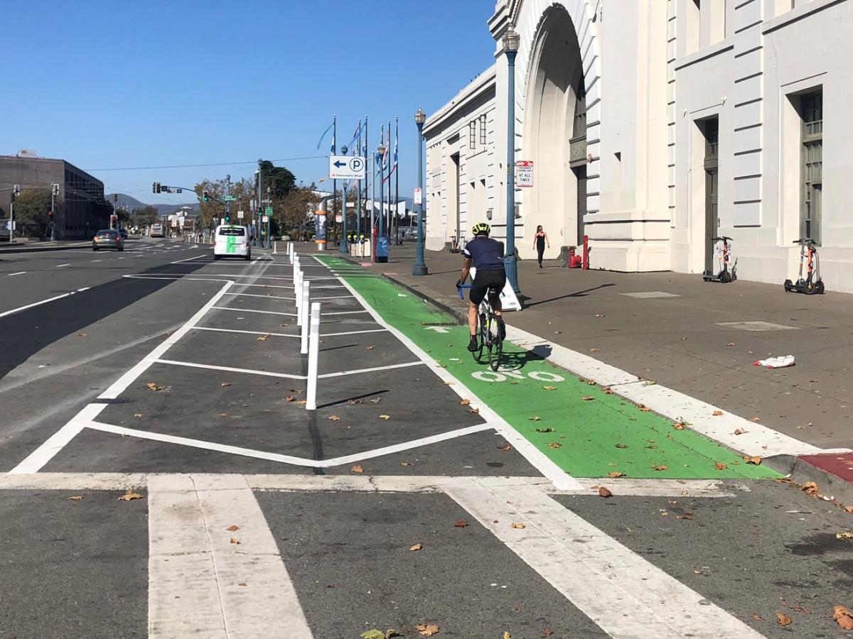 Person riding their bike past the Ferry Building on the green bike path