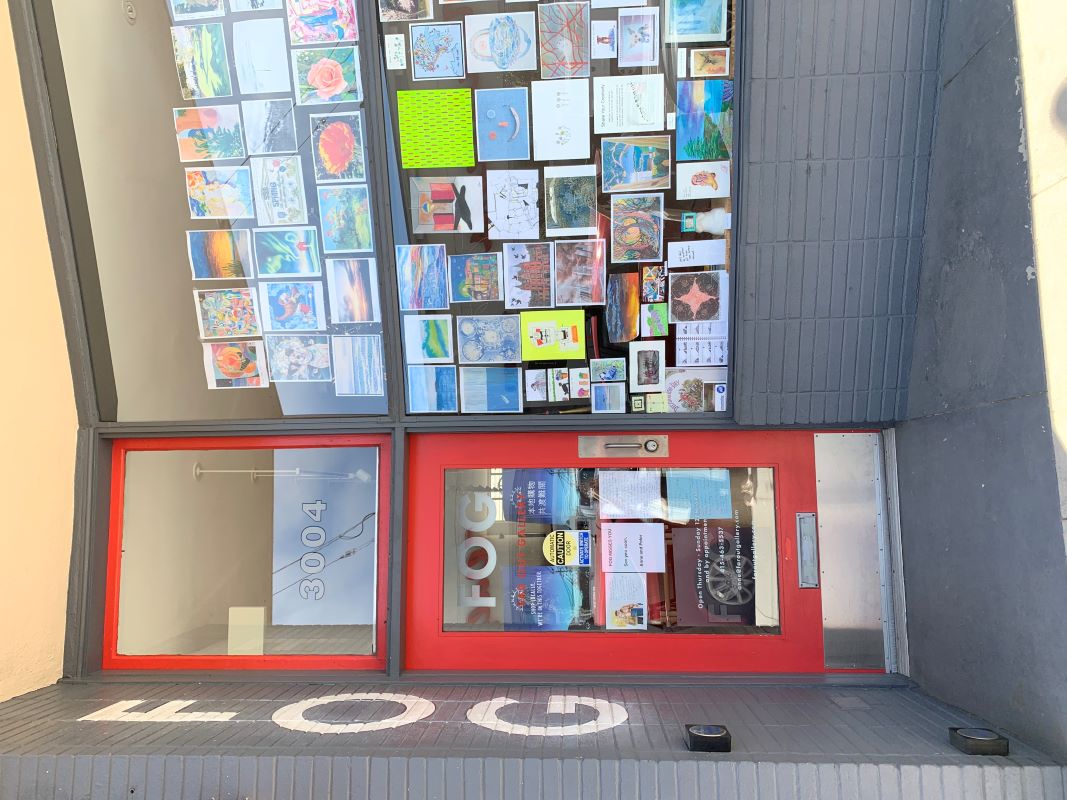 Picture of a store front with a large window filled with art work