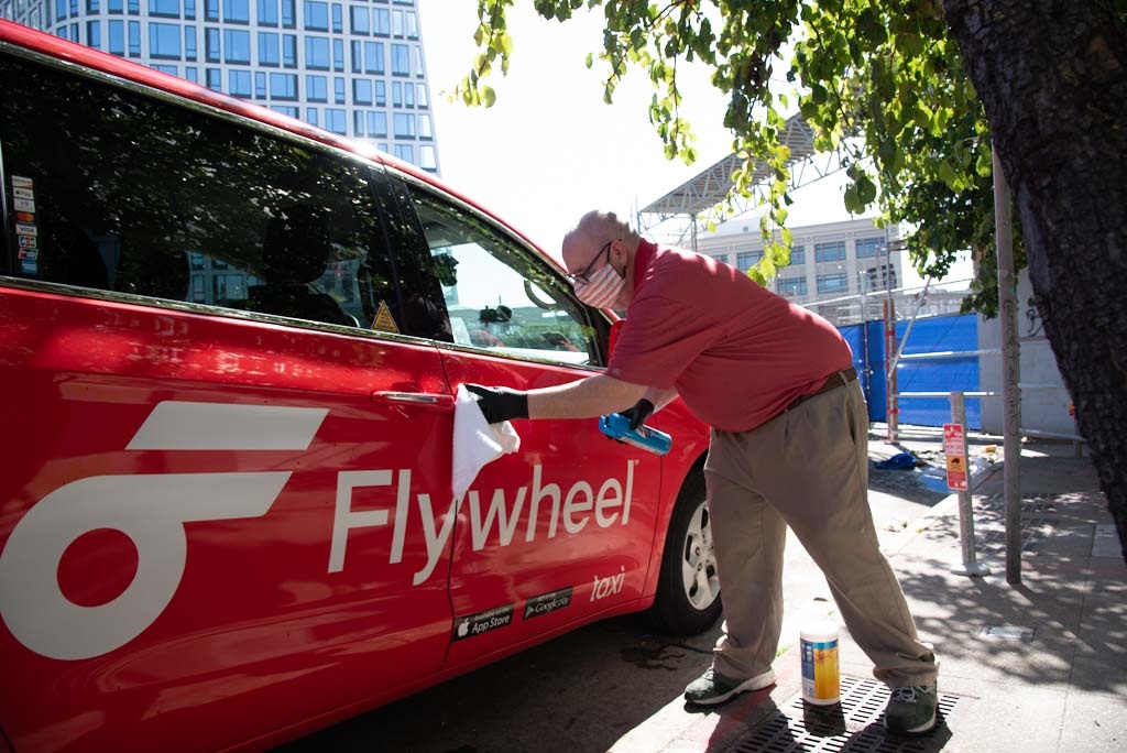 man cleaning outside of a red taxi