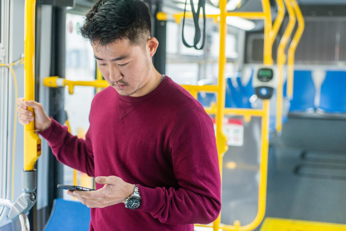 Man on bus checking his phone