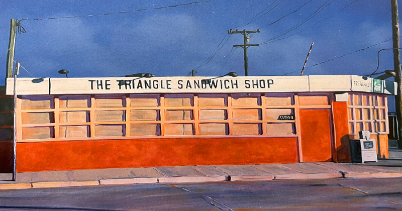 The Triangle Sandwich Shop in reddish-orange, with a closed sign and a sign advertising breakfast and Squirt. A newspaper box sits in front. To the right are a telephone pole and an industrial building. To the left are a parked U-Haul truck and a fragment of the downtown skyline. A sidewalk and street run in front.