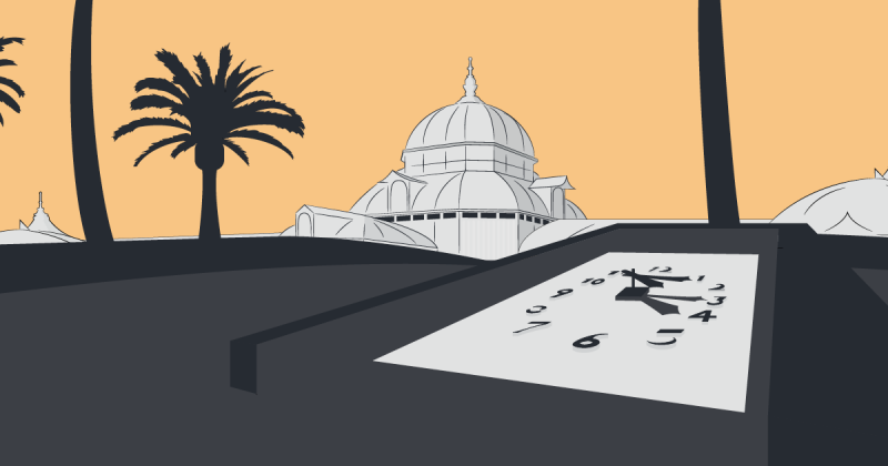 A clock face in the ground, hands pointing to 4:15. In the background are palm trees and the top of the Conservatory of Flowers.